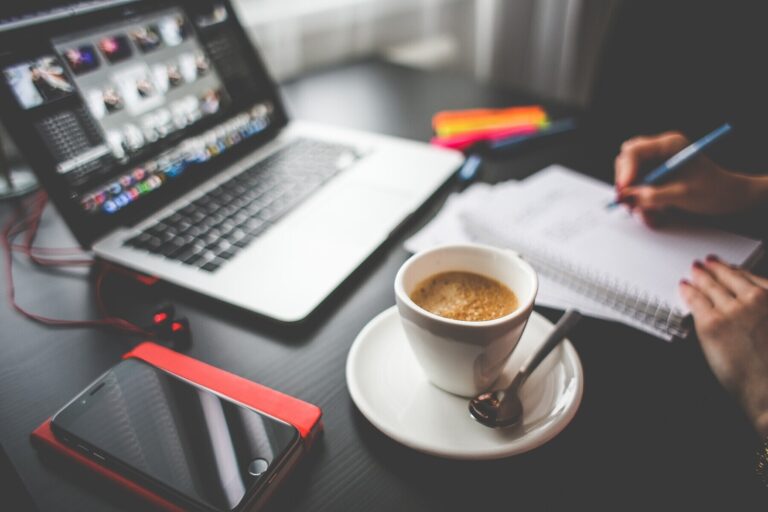 Ein Schreibtisch mit einem Laptop, einer Tasse Kaffee und Notizen.