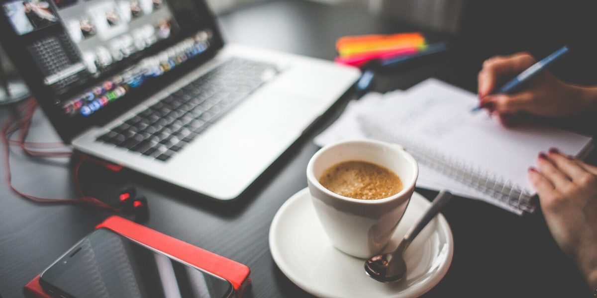 Ein Schreibtisch mit einem Laptop, einer Tasse Kaffee und Notizen.