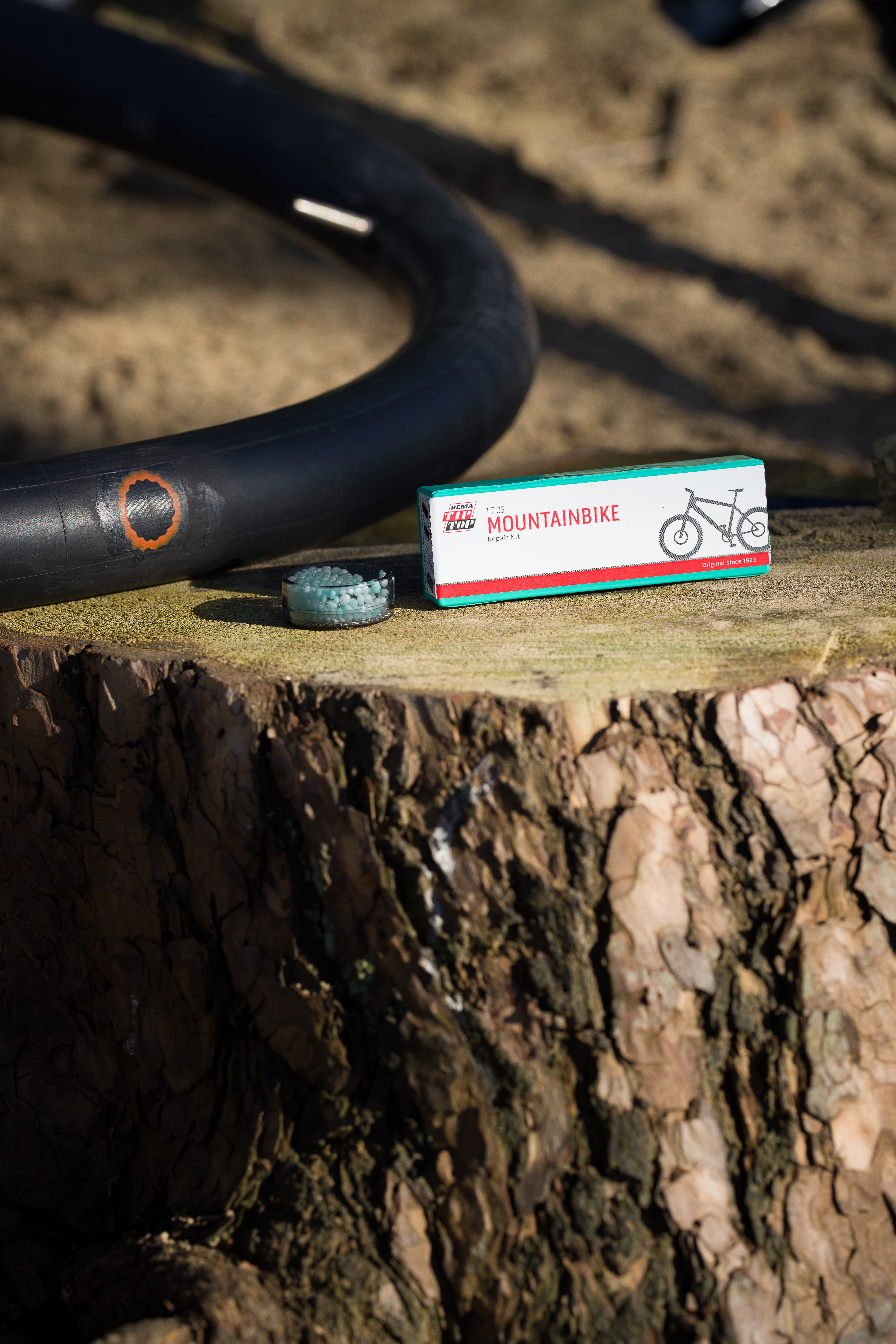 Fahrradreparatur-Kit neben einem Fahrradschlauch auf einem Baumstumpf